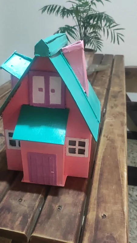 Casinha de boneca em rosa e verde-água, com telhado e janelas em relevo
